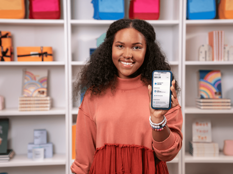 Girl holding a cell phone showing the Greenlight app experience