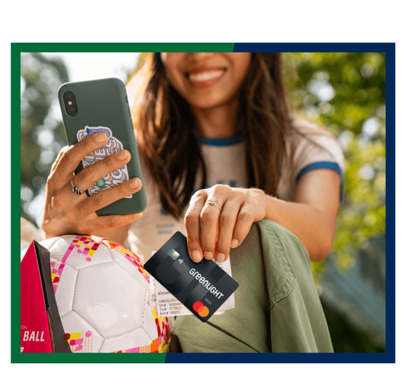 Woman holding Greenlight debit card