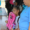 A child holding a backpack.