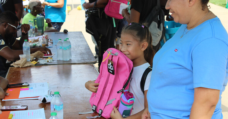 A child receiving a new backpack.