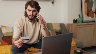 Man on his cell phone staring at his debit card