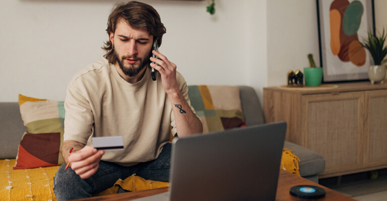 Man on his cell phone staring at his debit card