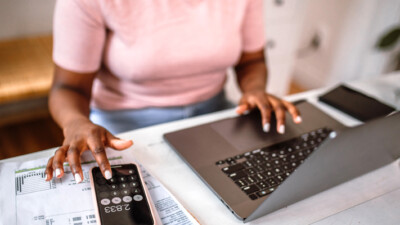 A woman using a laptop and her phone.